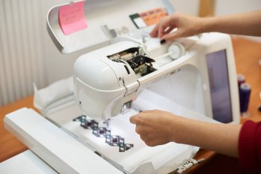 Dikiş makinesi üzerinde çalışan ve renkli geometrik desen beyaz Tekstil oluşturma eller, yakın çekim