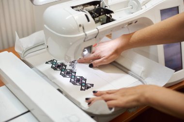 Dikiş makinesi üzerinde çalışan ve renkli geometrik desen beyaz Tekstil oluşturma eller, yakın çekim