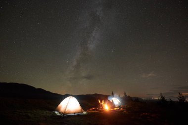 Grup dört turistler, kadın ve erkek dinlenme gece şenlik ateşi yakarak kamp 