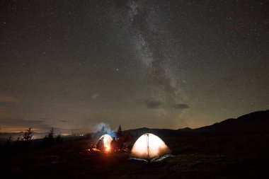 Grup dört turistler, kadın ve erkek dinlenme gece şenlik ateşi yakarak kamp 