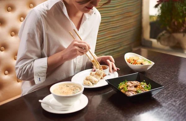 Cropped view of woman in white blouse with red lips ordering meal in luxury Japanese restaurant
