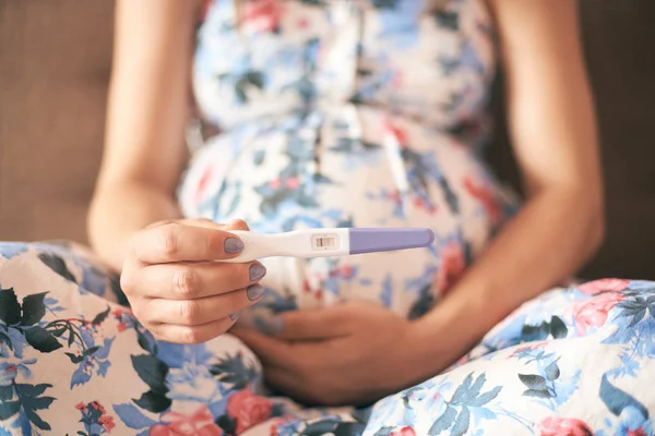 Zbliżenie Test Ciążowy Rękach Młoda Kobieta Sukni Siedzi Kanapie Domu — Zdjęcie stockowe