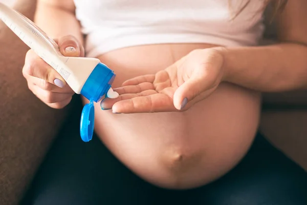 Foco Seletivo Mãos Femininas Mantendo Nata Aplicando Barriga Grande — Fotografia de Stock