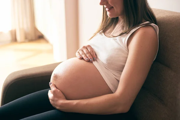 Widok Boku Ciąży Kobieta Białej Koszuli Siedzi Kanapie Domu Obejmując — Zdjęcie stockowe