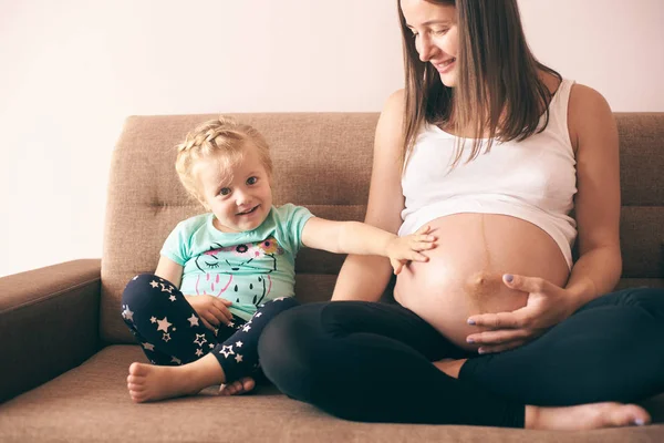 Piękne Dziewczyny Siedząc Kanapie Matki Ciąży Patrząc Kamery — Zdjęcie stockowe