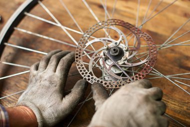 close up of mechanic working in bicycle repair shop fixing bike wheel using special tool clipart