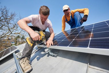 Male engineers installing solar photovoltaic panel system using screwdriver clipart