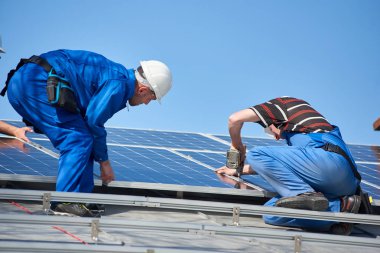 Mavi güneş pili modern ev çatıda montaj elektrikçiler. Alternatif yenilenebilir enerji ekolojik kavram.