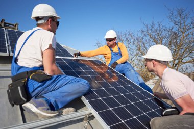 Üç elektrikçiler mavi güneş pili modern ev çatıda montaj