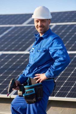 Mavi takım elbise ve koruyucu kask güneş fotovoltaik panel sistemi yükleme erkek işçi portresi