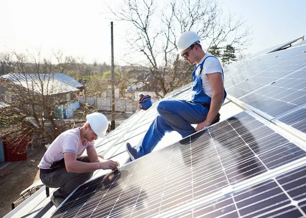 現代の家の屋根の上の青い太陽電池モジュールを取り付け電気技師 代替再生可能エネルギー生態学的な概念 — ストック写真