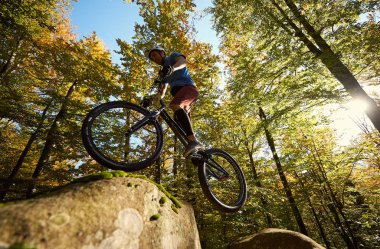 Profesyonel bisikletçi mahkemeye büyük kayanın üzerinde bisiklet atlama