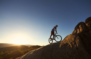 Profesyonel bisikletçi bisiklet büyük kayanın üzerine mahkemeye Dengeleme silüeti