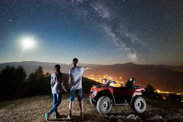 Happy romantic couple man and woman tourists with atv quad motorbikes on top of mountain