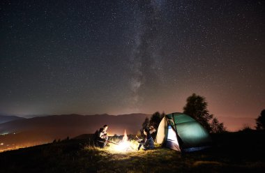 Işıklı turist çadır kampında dinlenme genç mutlu çift yürüyüşçü