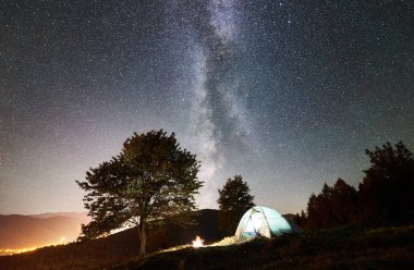 parlayan çadır ve şenlik ateşi altında inanılmaz gece gökyüzünde yıldızlar ve Samanyolu dolu