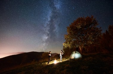 Mutlu çift yürüyüşçü yakınındaki parlayan turist çadır kamp ateşi, geceleyin dinlenme 