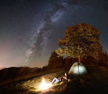 kamp ateşi turizm çadır kamp ve aydınlatmalı ve gece gökyüzünde yıldızlar ve Samanyolu dolu zevk görünümünü yanında, istirahat kadın turist