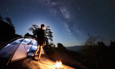 Kamp, şenlik ateşi ve ışıklı turist çadır yanında kayalık dağ üstüne yaz geceleri istirahat genç uzun yürüyüşe çıkan kimse adam