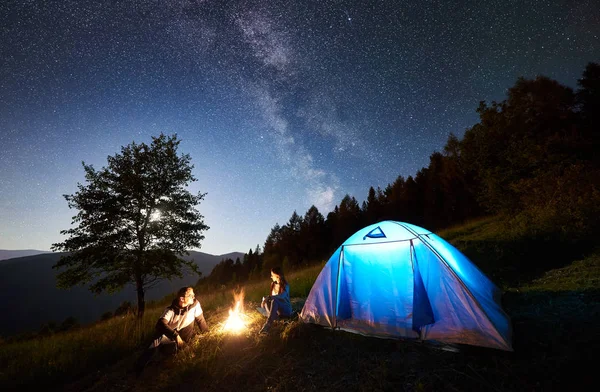 Młoda Para Odpoczynek Przy Ognisku Obok Tourist Camp Niebieski Namiot — Zdjęcie stockowe
