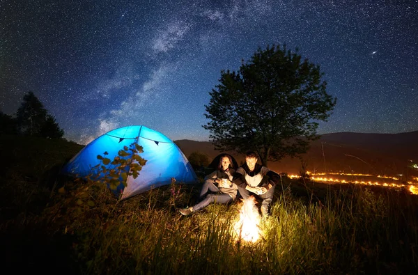 Jovem Casal Descansando Fogueira Lado Acampamento Barraca Turística Azul — Fotografia de Stock