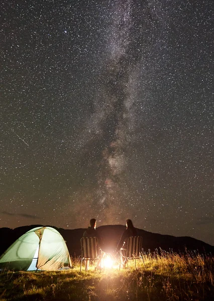 Young couple tourists resting at summer night camping in mountains