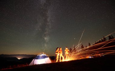 birlikte yanında aydınlatmalı turist çadır kamp ateşi etrafında oturan arkadaşlar backpackers