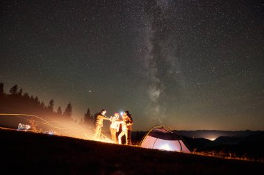 Birlikte şenlik ateşi dinlenme ve gece, çadır yakınındaki tatil keyfini genç arkadaşlar turist