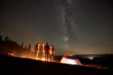 Birlikte şenlik ateşi dinlenme ve gece, çadır yakınındaki tatil keyfini genç arkadaşlar turist