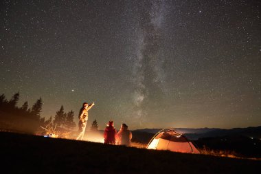 Mutlu arkadaş yürüyüşçü birlikte geceleyin yanında kamp ve turistik çadır kamp ateşi etrafında oturan