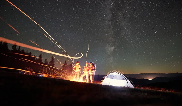 Amigos Mochileiros Descansando Juntos Torno Fogueira Lado Tenda Turística Iluminada — Fotografia de Stock