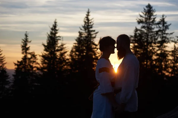 晚上站在山顶上的恋爱中的年轻夫妇剪影 — 图库照片