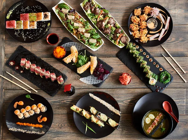 Serving tasty sushi rolls and other traditional japanese food on wooden table in restaurant