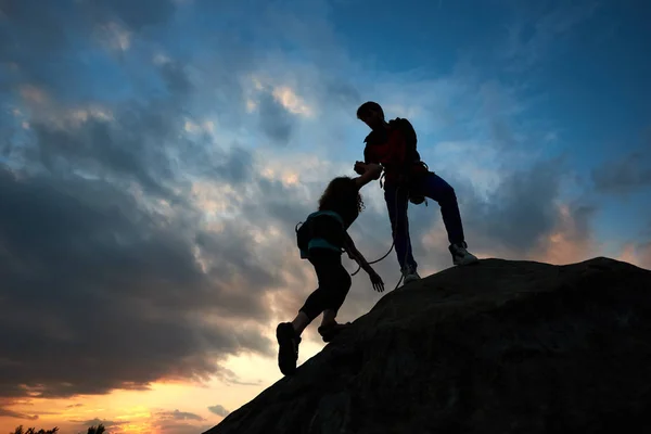 Siluetas Pareja Hombres Mujeres Escaladores Ayudándose Unos Otros Subir Montaña — Foto de Stock
