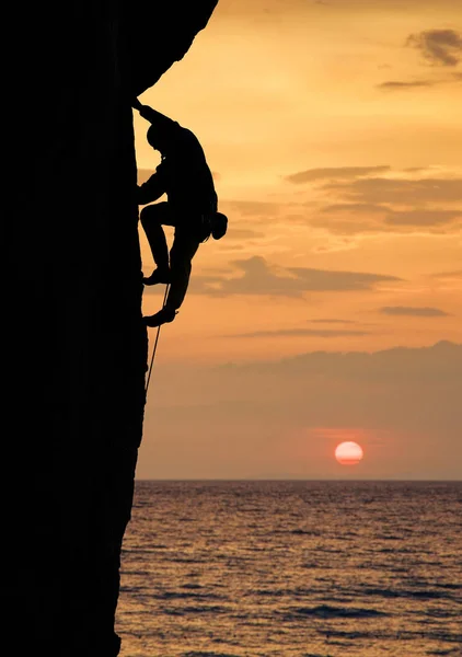 Silhueta Alpinista Sexo Masculino Subindo Alto Penhasco Reto Pôr Sol — Fotografia de Stock