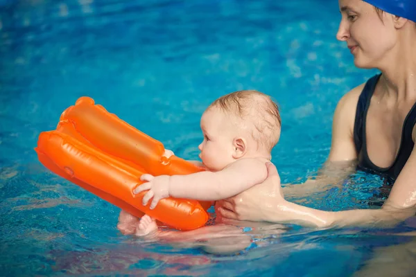 Inflatable orange toy helping little child staying on water and not sinking in swimming pool