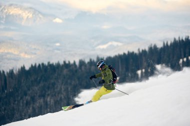 Sırt çantalı usta kayakçı yamaçtan aşağı doğru koşuyor.