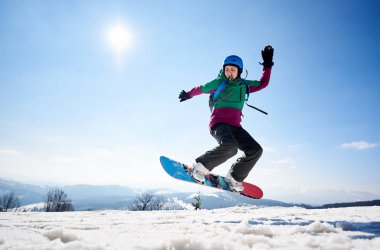 Genç bayan snowboardcu fotokopi alanında kayak yapıyor açık mavi gökyüzü ve güneşli kış günlerinde karlı dağlar.