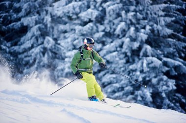 Skier with backpack doing freeride-descent on snow-covered slope in white snow powder blizzard clipart