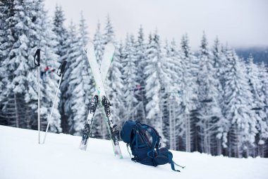 Turist sırt çantası, kayak ve sırıklar dağdan inerken kara serilmiş.