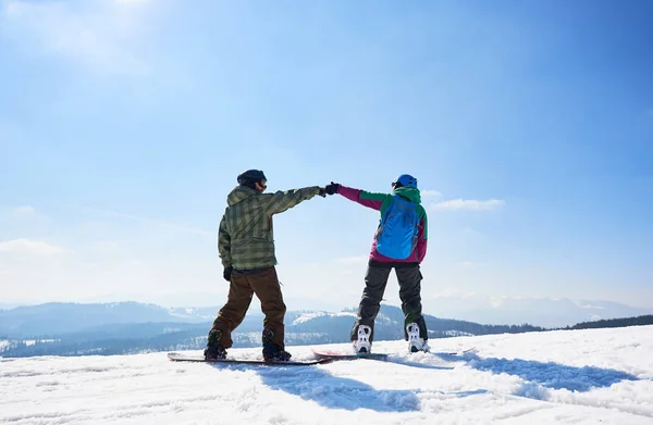 晴れた冬の日に青空と木々の山々のコピースペースの背景に山の頂上に2人の幸せな観光客のスノーボーダーのバックビュー — ストック写真