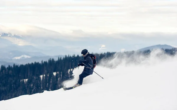 深い白い雪の粉で山から降りるフリーダースキーヤーのサイドビュー — ストック写真