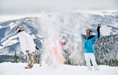 Canlı kış sporları takımları giymiş bir grup arkadaş dağlarda kar altında eğleniyorlar. Anın tadını çıkarırken kar kusuyordu. Kış eğlencesi