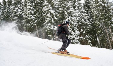 Spruce Ormanı boyunca kayak yapan kayakçının yan görüntüsü. Karda dengeyi sağlamak. Aşırı kış sporu kavramı. Sezon eğlencesi