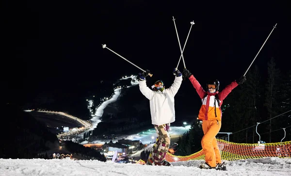 Vrolijke Mannelijke Vrouwelijke Skiërs Winterjassen Helmen Verhogen Skistokken Vreugdevolle Jongeman — Stockfoto