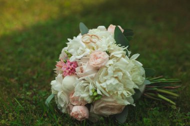 Yakın çekim yaz yeşil çim üzerinde gelin düğün buket güzel altın alyans.