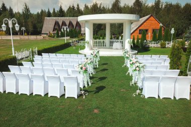 Yaz aylarında açık havada evlilik töreni. Bir düğün beyaz sandalye ve güzel çiçekler ile yer.