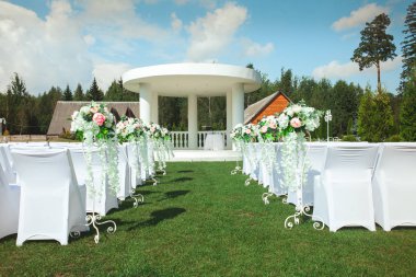Yaz aylarında açık havada evlilik töreni. Bir düğün beyaz sandalye ve güzel çiçekler ile yer.