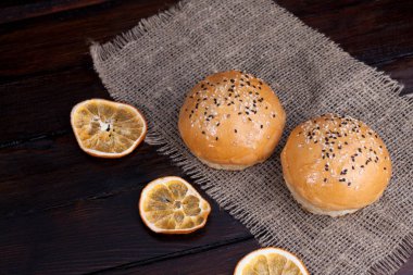 Rustik ahşap arka plan üzerinde sıcak tatlı çörekler. Gıda ile susam kumaş ve kuru portakal şeklinde