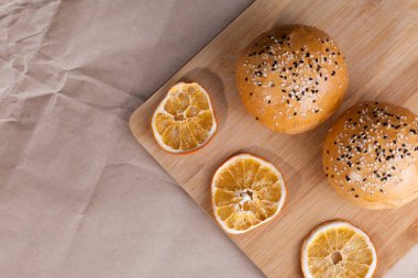 Rustik bir arka plan üzerinde sıcak tatlı çörekler. Susam kuru portakal ile kesme tahtası üzerinde ile şekilli gıda